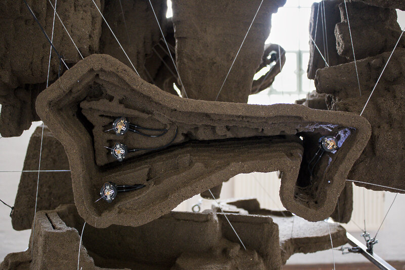 A detail shot showing on of the structures in detail. It resembles the shape of an open-pit mine. Four small machines are nested inside of it.