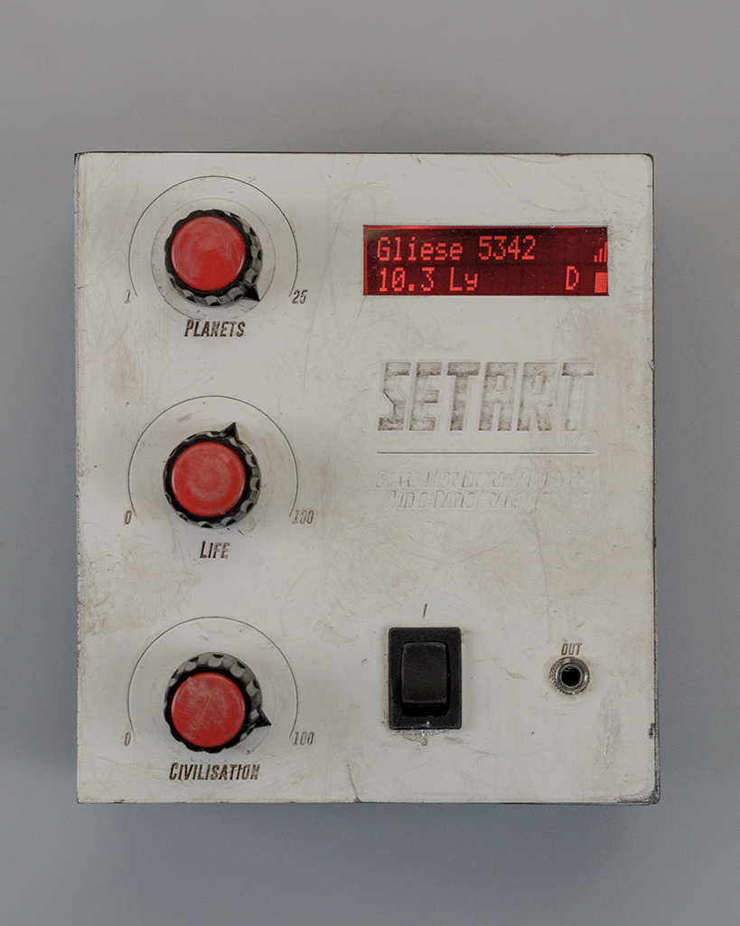 The cover of the SETART shown in detail. Its white surface is riddled with scratches and dirt. The three rotating knobs are titled Planets, Life and Civilisation. The red LCD shows the name Gliese 5342, a distance of 10.3 Lightyears and indicates it to be a class D star.