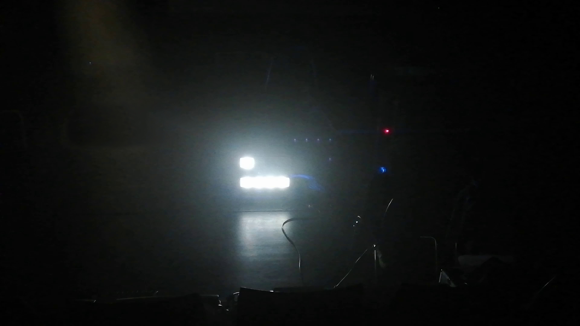 Five rectangular lights arranged next to each other shine directly into the camera. Next to them the faint structures of another machine, connected with wires, are visible.